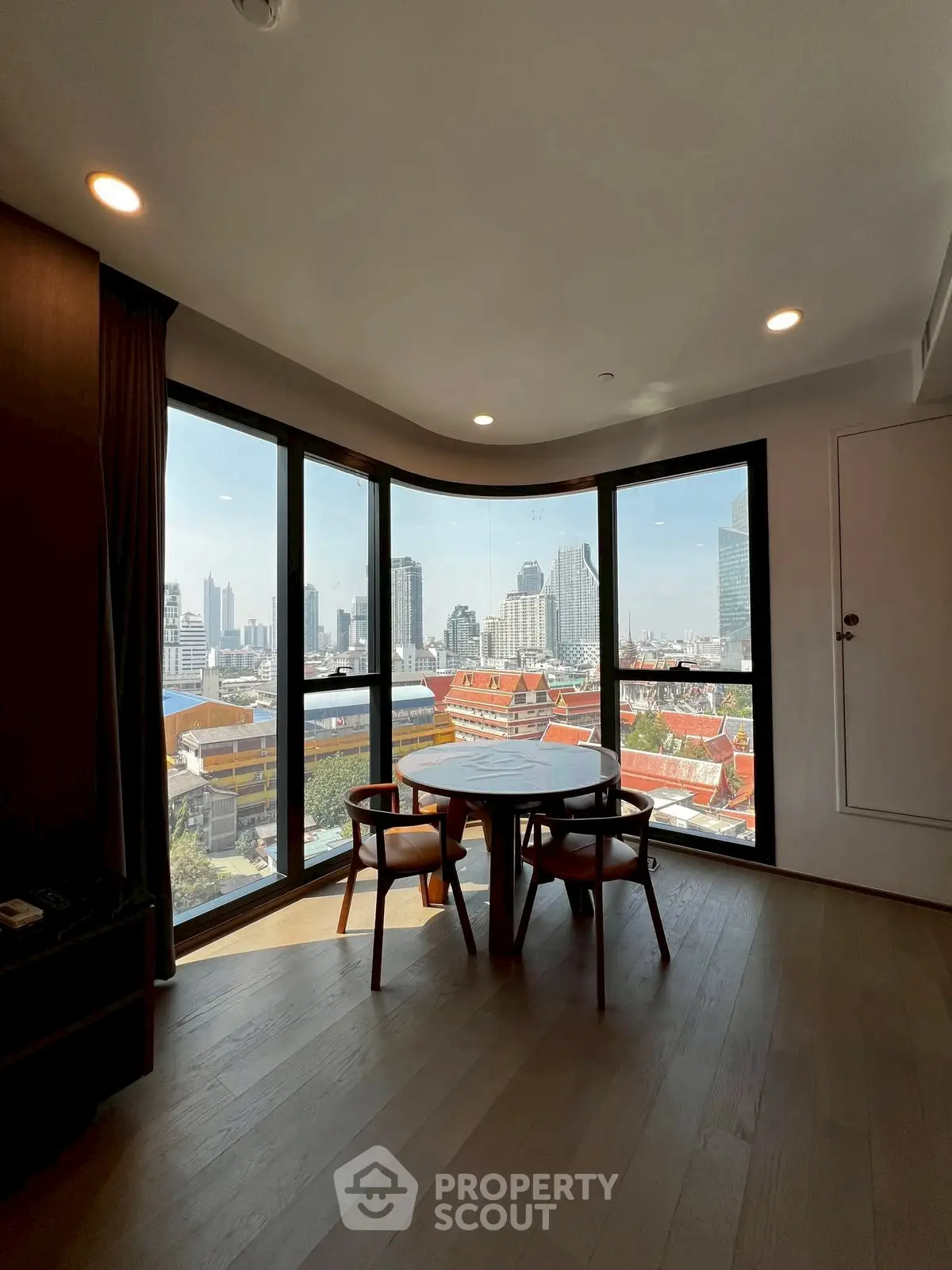 Stunning city view from modern high-rise apartment with floor-to-ceiling windows.