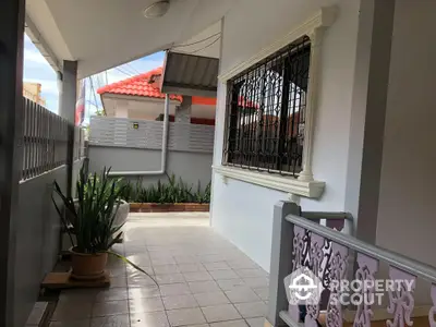 Charming residential entrance with decorative railing and potted plants, offering a welcoming ambiance.