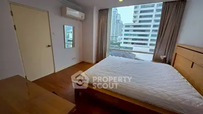 Spacious bedroom with city view and modern furnishings in high-rise apartment.