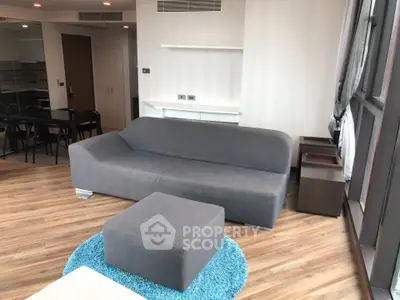 Modern living room with sleek gray sofa and vibrant blue rug in a stylish apartment.