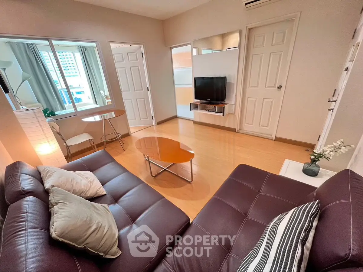 Modern living room with stylish furniture and natural light, featuring a cozy sofa and a flat-screen TV.