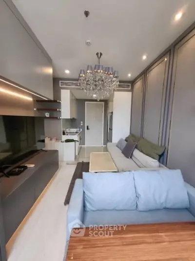 Modern living room with elegant chandelier and sleek furniture in a stylish apartment.