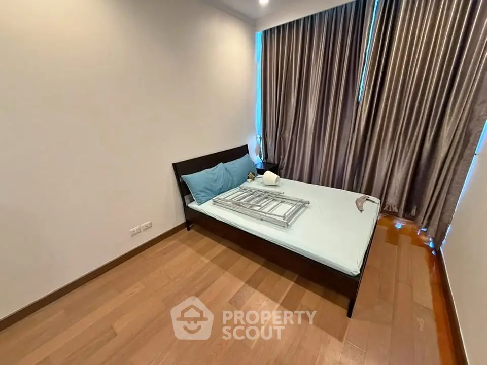 Spacious bedroom with wooden flooring and elegant curtains in modern apartment.
