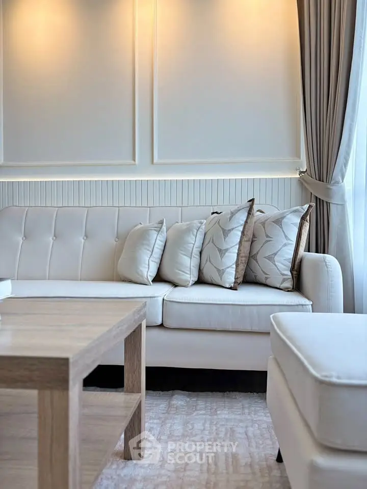 Elegant living room with modern sofa, stylish cushions, and natural light from large window.