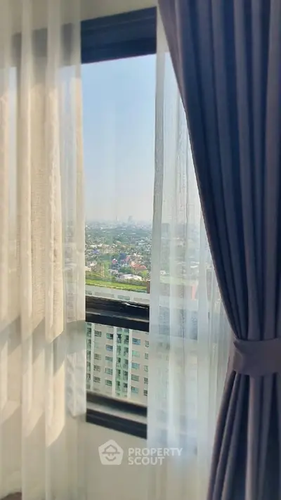 Stunning high-rise view from a modern apartment window with elegant curtains.