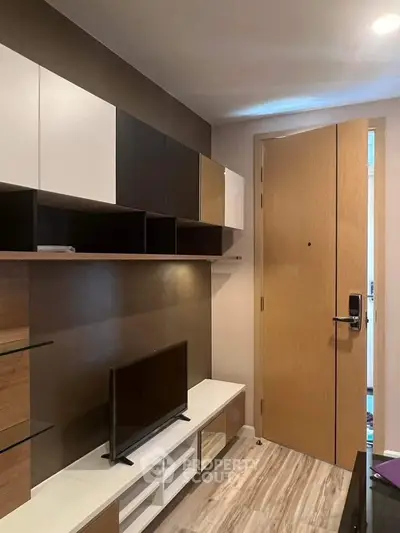 Modern living room with stylish shelving and TV unit, featuring a sleek wooden door and contemporary design.