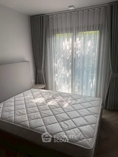 Bright bedroom with large window and elegant curtains, featuring a comfortable bed and serene ambiance.
