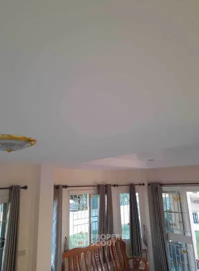 Spacious living room with large windows and elegant wooden furniture.