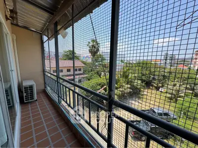 Spacious balcony with safety netting and scenic view of greenery and rooftops.