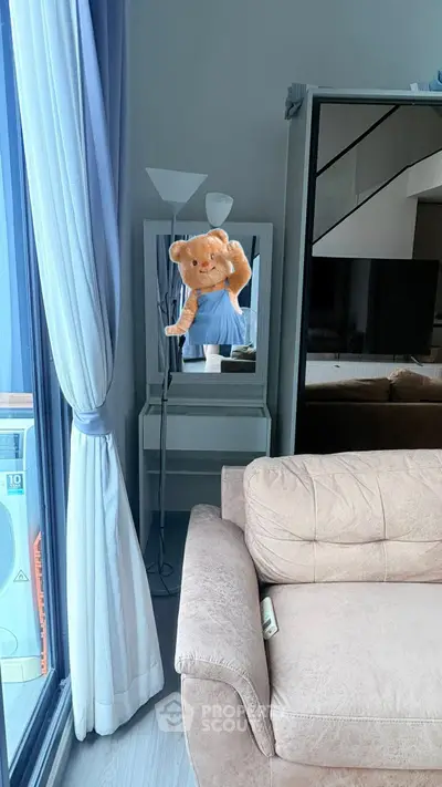 Cozy living room with plush sofa and stylish decor, featuring a unique teddy bear mirror reflection.