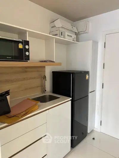 Modern compact kitchen with sleek black fridge and microwave