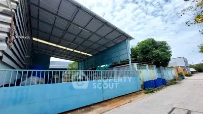 Industrial warehouse exterior with blue fencing and open roof structure