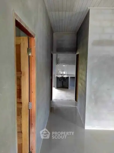 Modern minimalist hallway leading to a sleek kitchen area with polished concrete floors.