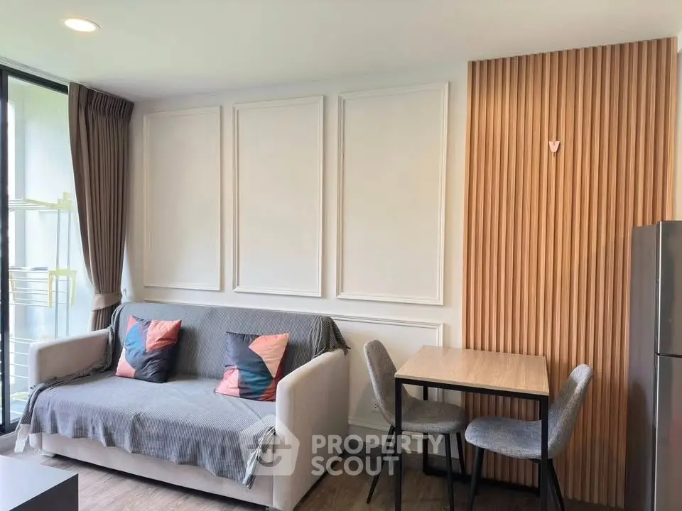 Modern living room with stylish sofa, dining table, and elegant wall paneling, perfect for cozy urban living.