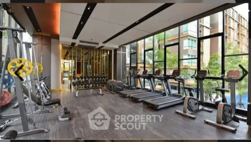 Modern gym with state-of-the-art equipment and large windows in luxury apartment complex.