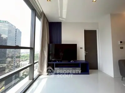 Modern living room with large windows and city view, featuring sleek TV setup.