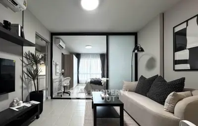 Modern living room with stylish decor and view into a cozy bedroom