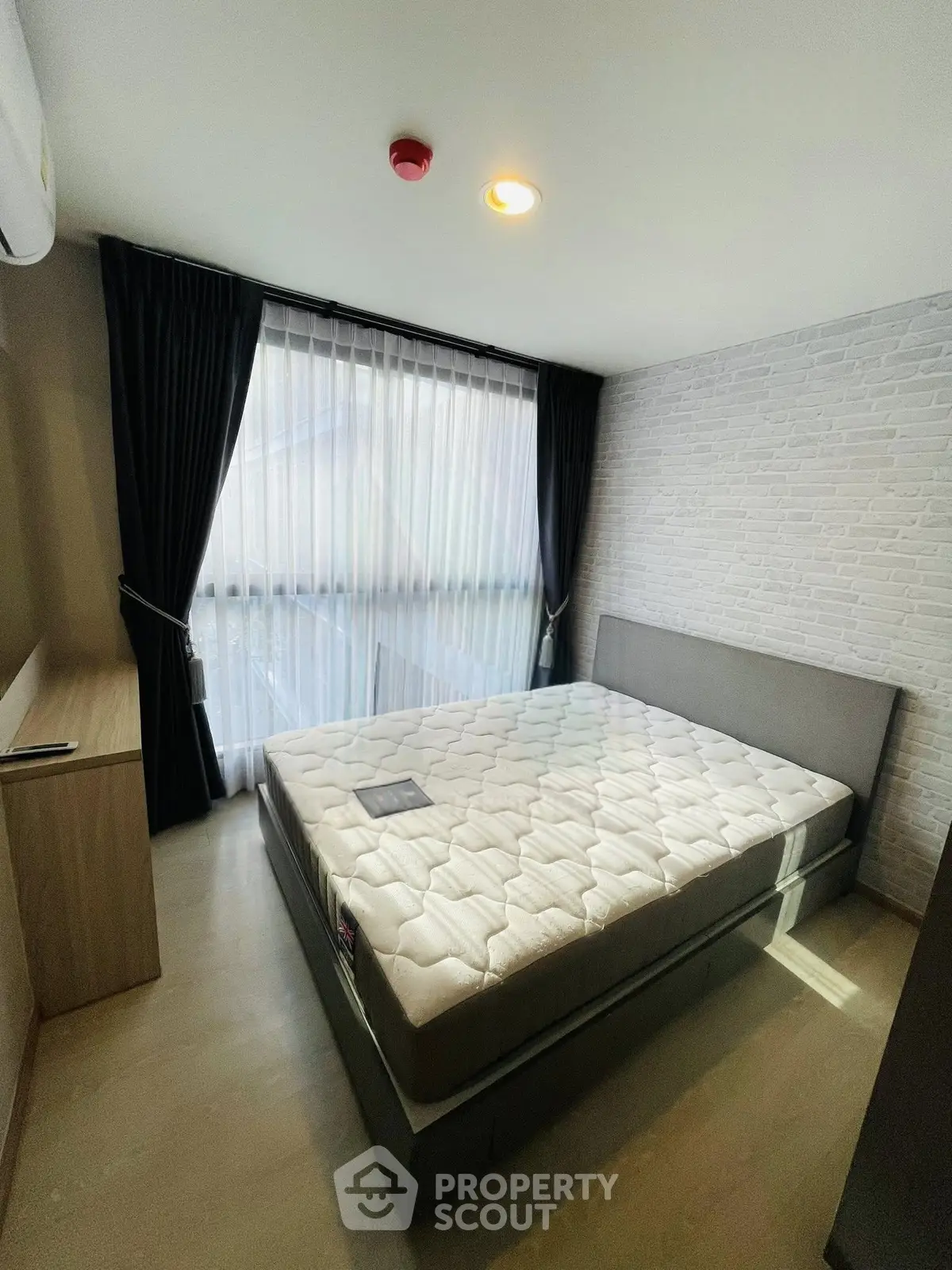 Modern bedroom with large window and stylish decor in a contemporary apartment.