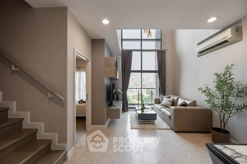 Spacious modern living room with high ceilings and city view, featuring elegant decor and natural light.