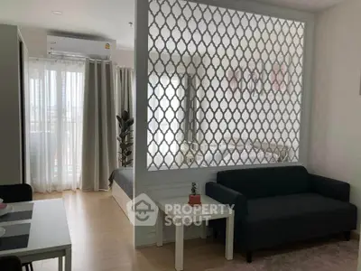 Modern apartment interior with stylish partition, cozy living area, and natural light from large windows.