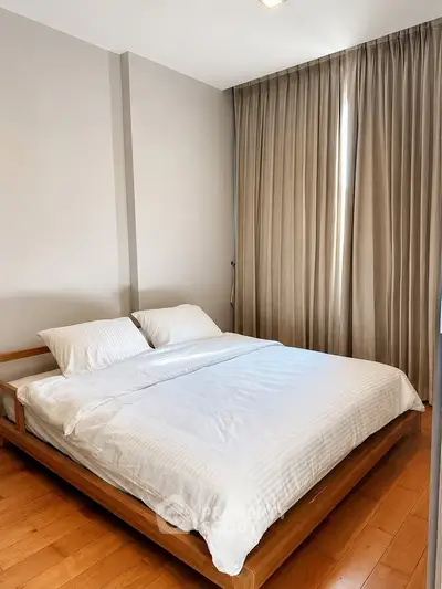 Spacious bedroom with elegant wooden flooring and cozy bed setup