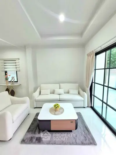 Modern living room with white sofas and large window, bright and inviting space.