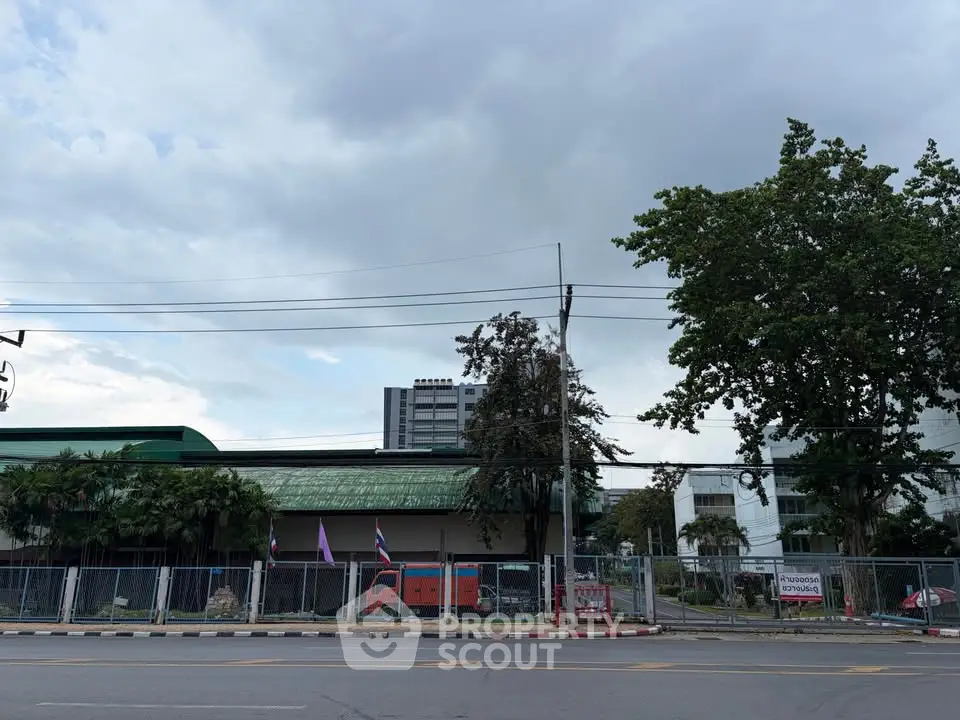 Street view of a commercial building with trees and a fenced area, ideal for business opportunities.