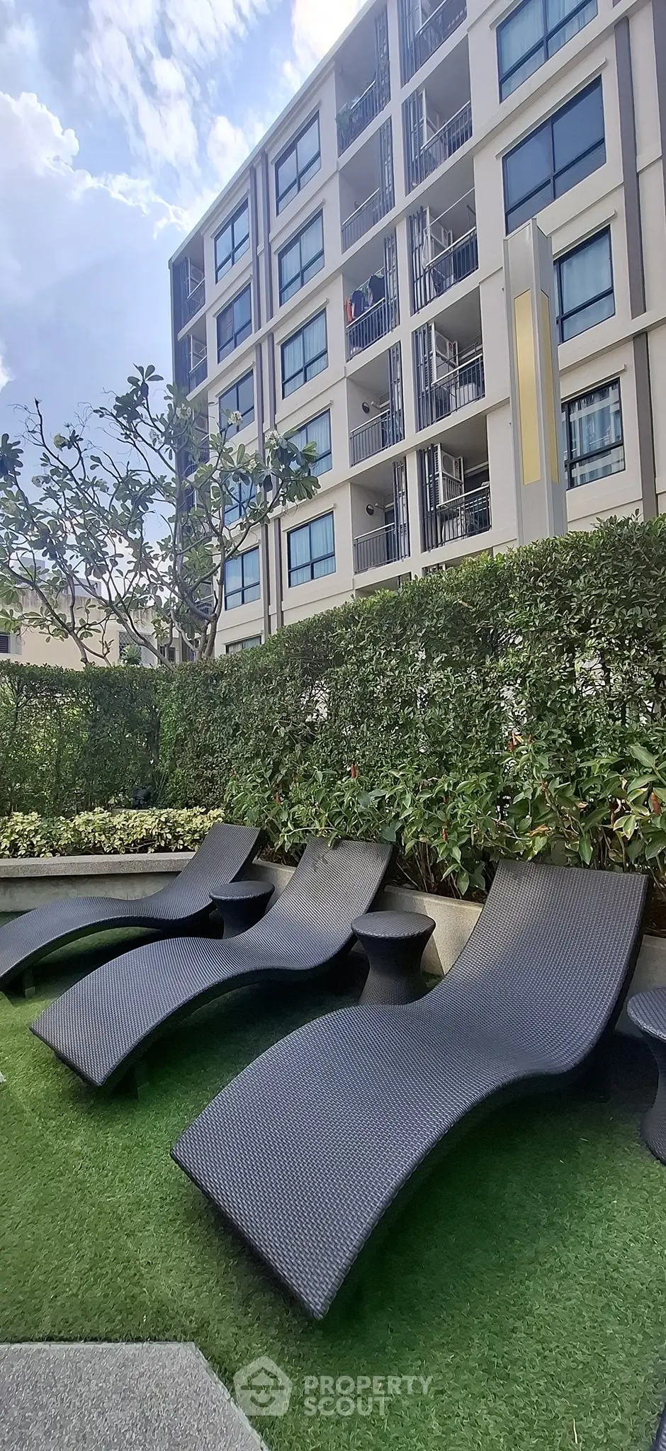 Modern apartment building with stylish outdoor lounge area and lush greenery