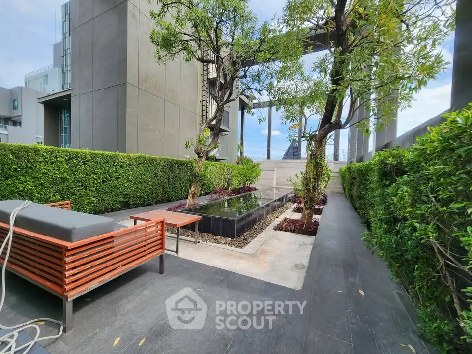 Modern rooftop garden with lush greenery and stylish seating area in urban setting.