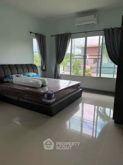 Spacious bedroom with large windows and modern furnishings, offering a serene view and ample natural light.