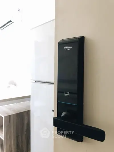 Modern apartment entrance with electronic lock and glimpse of kitchen area.