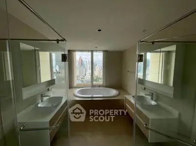 Luxurious bathroom with city view, featuring dual sinks and a central bathtub.