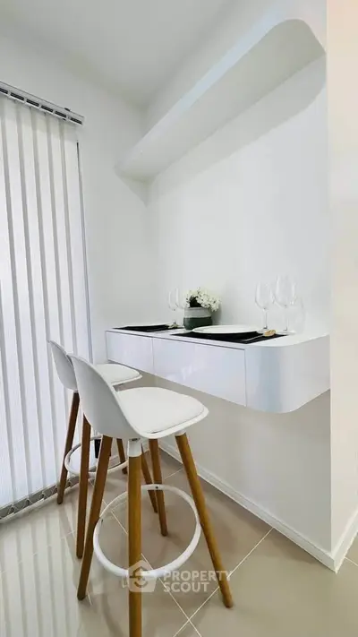 Modern minimalist kitchen corner with sleek white bar stools and floating shelf