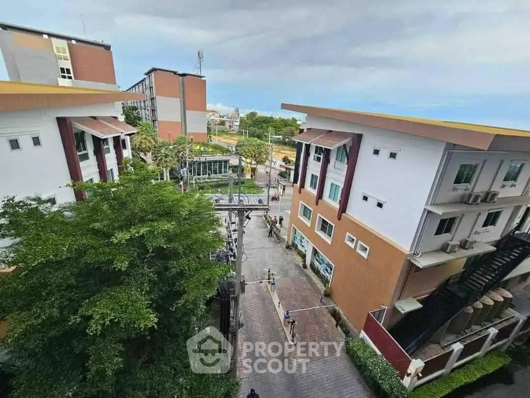Aerial view of modern residential buildings with lush greenery and clear sky.