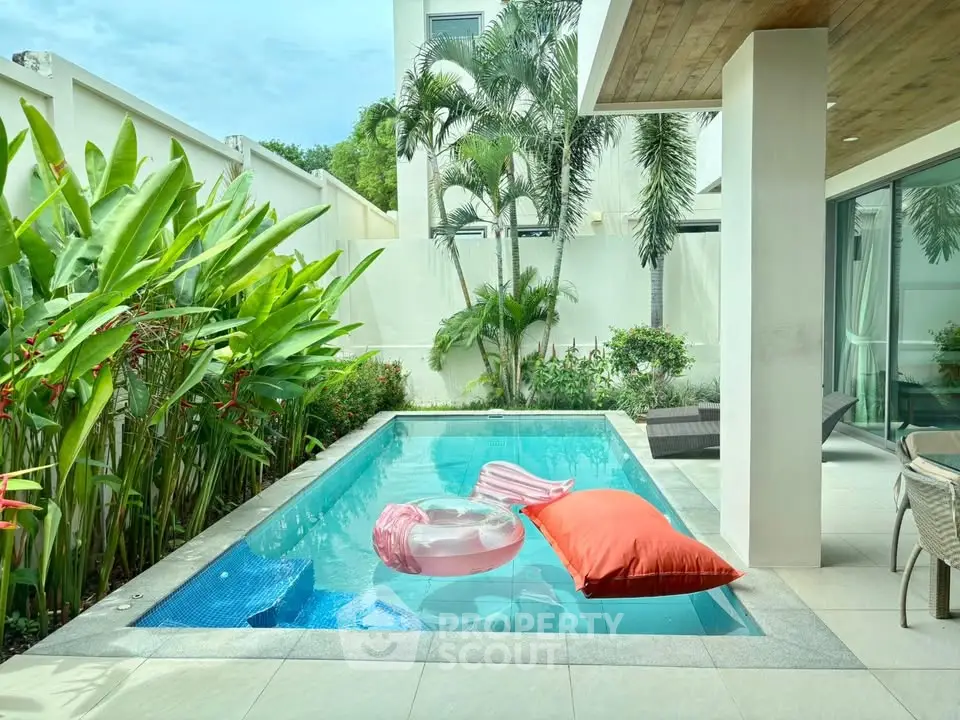 Luxurious private pool with lush greenery and modern patio in a tropical villa setting.