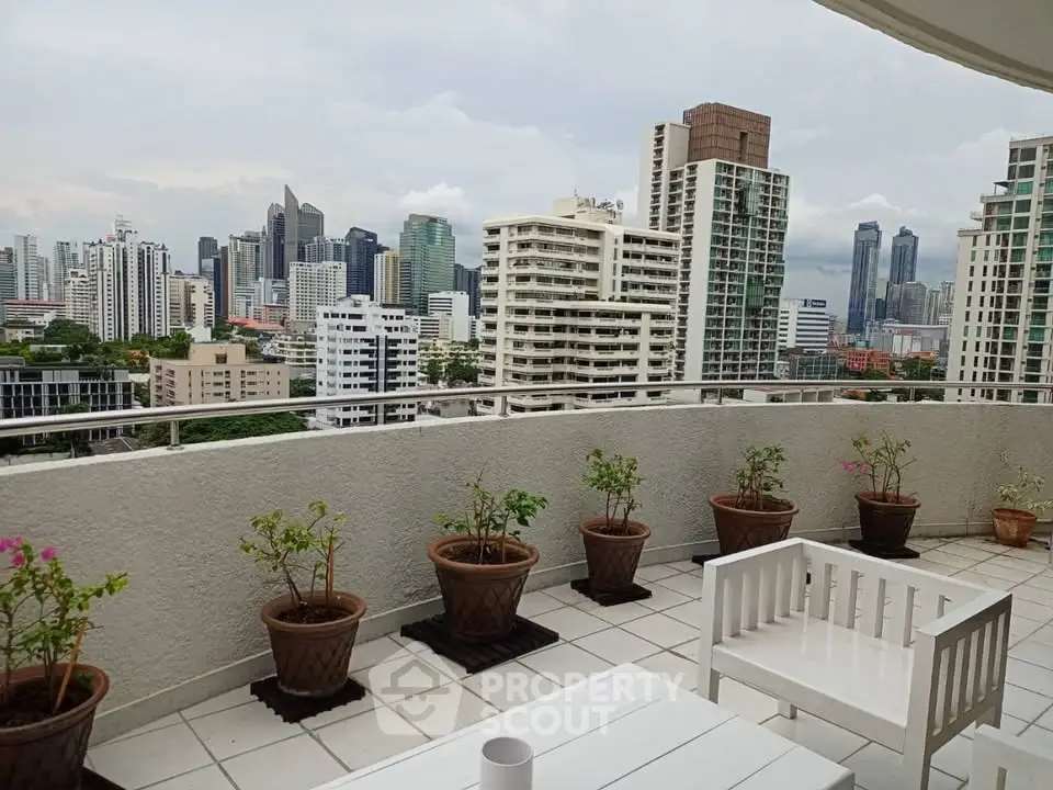 Spacious balcony with stunning city skyline view and potted plants, perfect for relaxation.