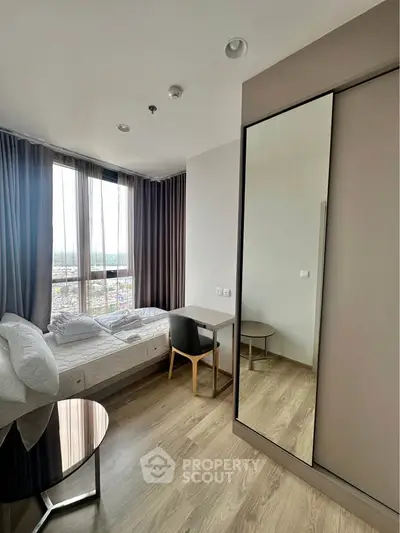 Modern bedroom with large window and sleek furniture in high-rise apartment.