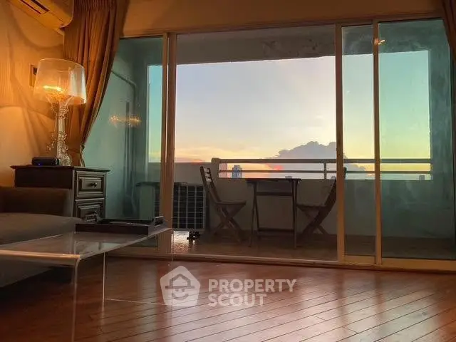 Charming living room with sunset view from balcony, featuring elegant decor and wooden flooring.