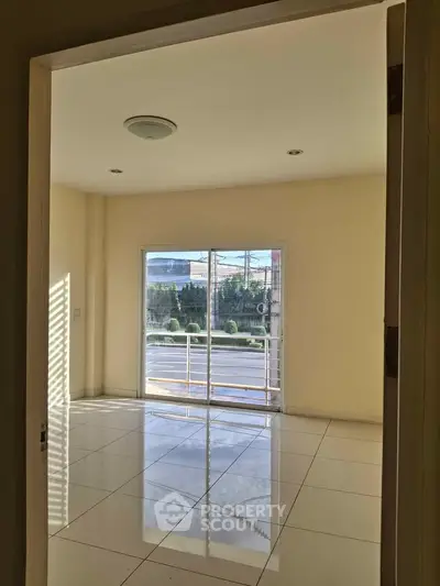 Spacious empty room with large window and glossy tiled floor