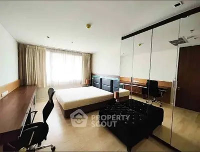 Spacious bedroom with modern furniture and large mirrored wardrobe