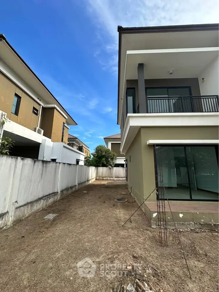 Modern two-story house with large windows and spacious backyard, perfect for family living.