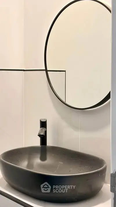 Modern bathroom with sleek black sink and round mirror