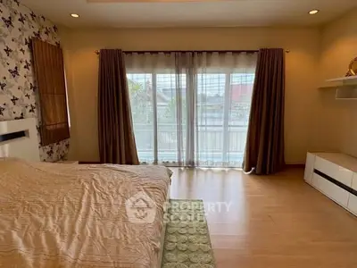 Spacious bedroom with large windows and elegant decor, perfect for relaxation and comfort.