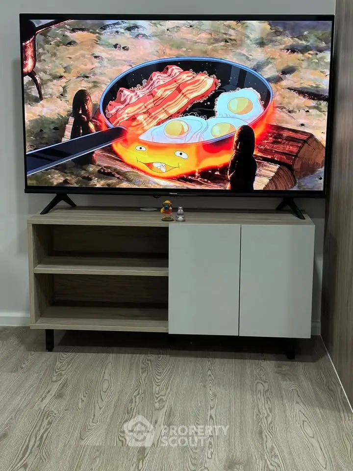 Modern living room with stylish TV stand and flat-screen TV displaying animated cooking scene.