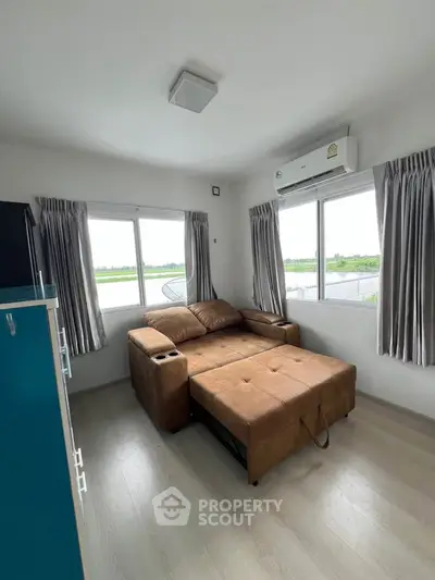 Cozy living room with brown sofa bed and large windows offering scenic views.