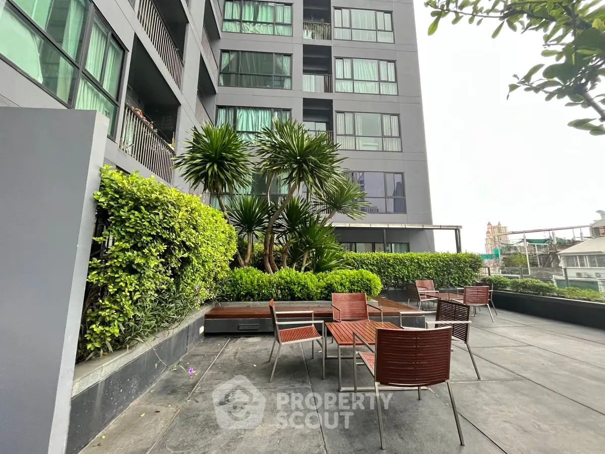 Modern apartment building with outdoor seating area and lush greenery