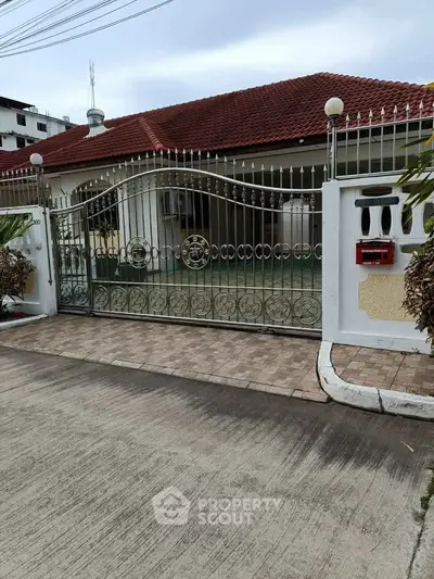 Charming single-story home with red-tiled roof and ornate metal gate in a serene neighborhood.