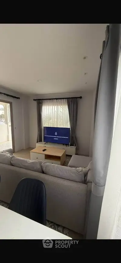 Modern living room with cozy sofa and large window, perfect for relaxation and entertainment.