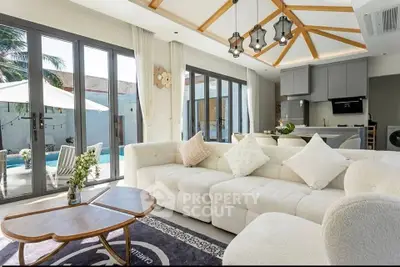Luxurious living room with modern open kitchen and pool view, featuring elegant decor and natural light.