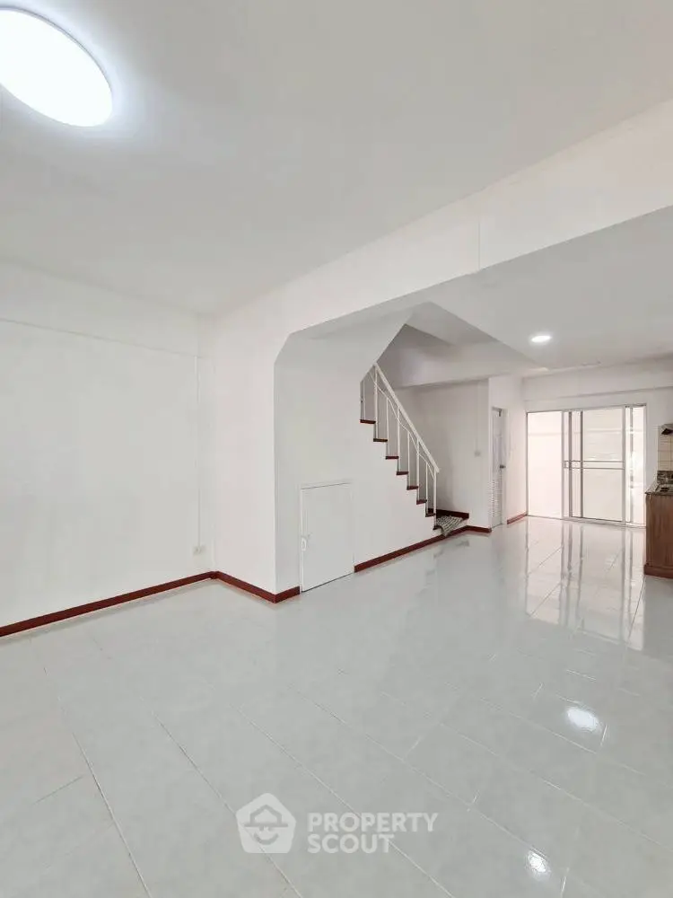 Spacious open-plan living area with modern staircase and tiled flooring.